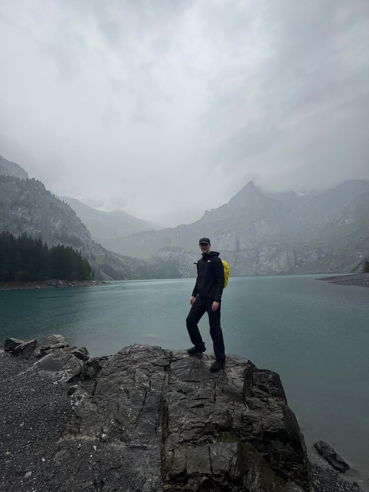 Chiel op een rots aan een turquoise bergmeer, met bergen in de mist